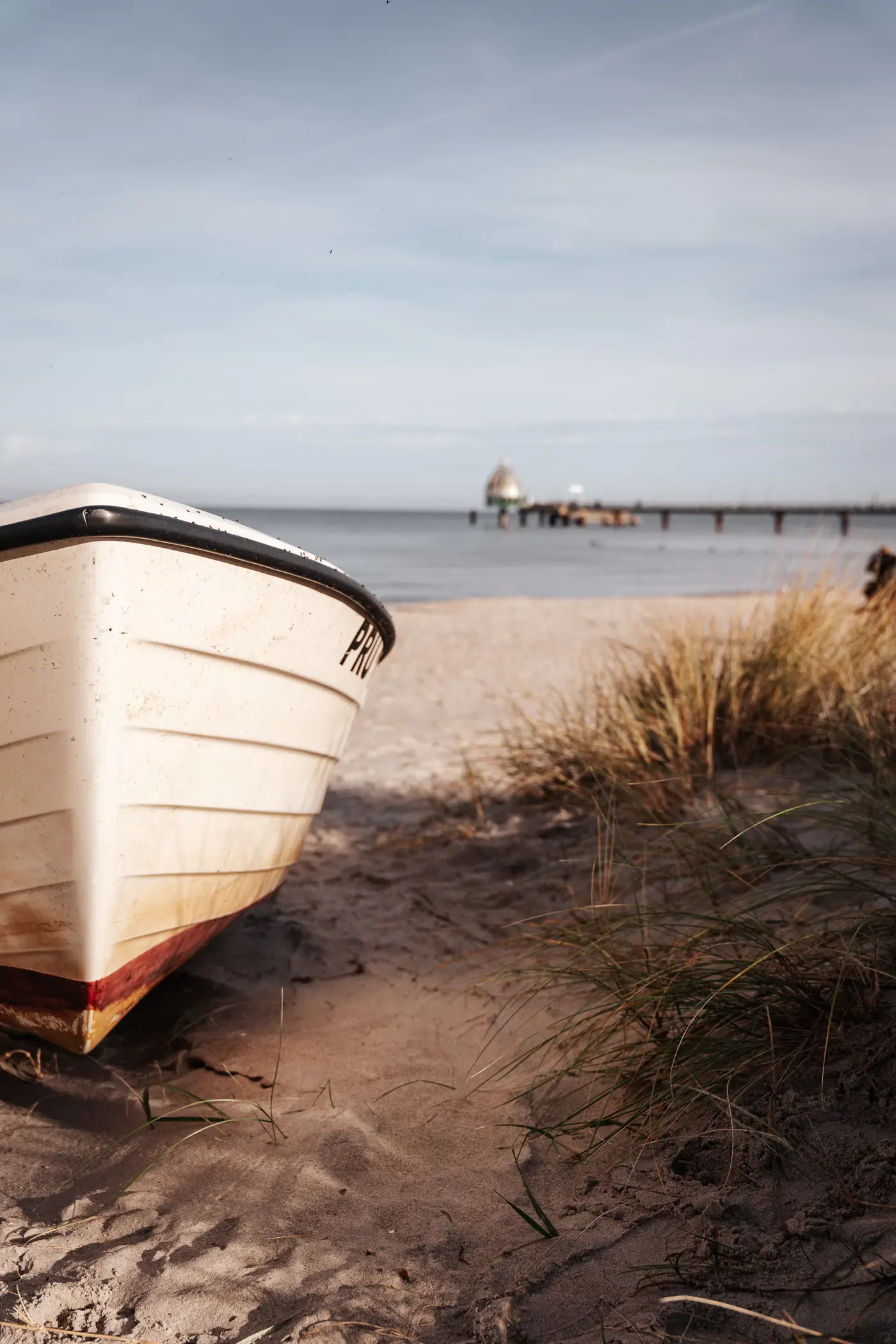 Boot am Strand mit Seebrücke Zingst im Hintergrund
